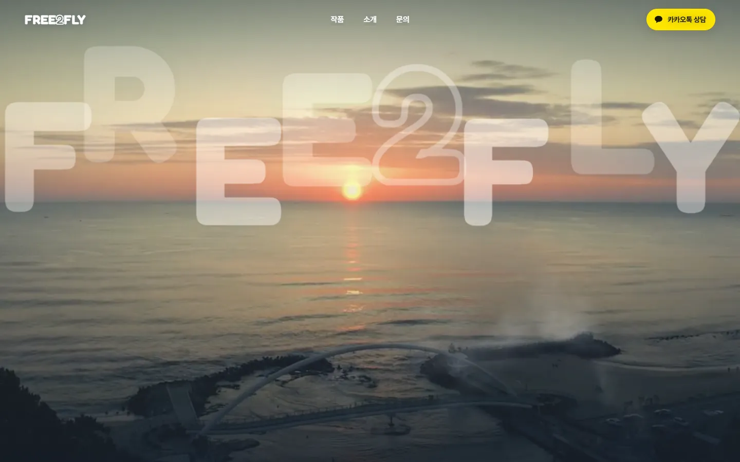 새로운 홈페이지 — 안개가 걷히며 FREE2FLY 글자가 흩어지고 하늘에서 찍은 바다 노을 영상이 펼쳐지는 화면